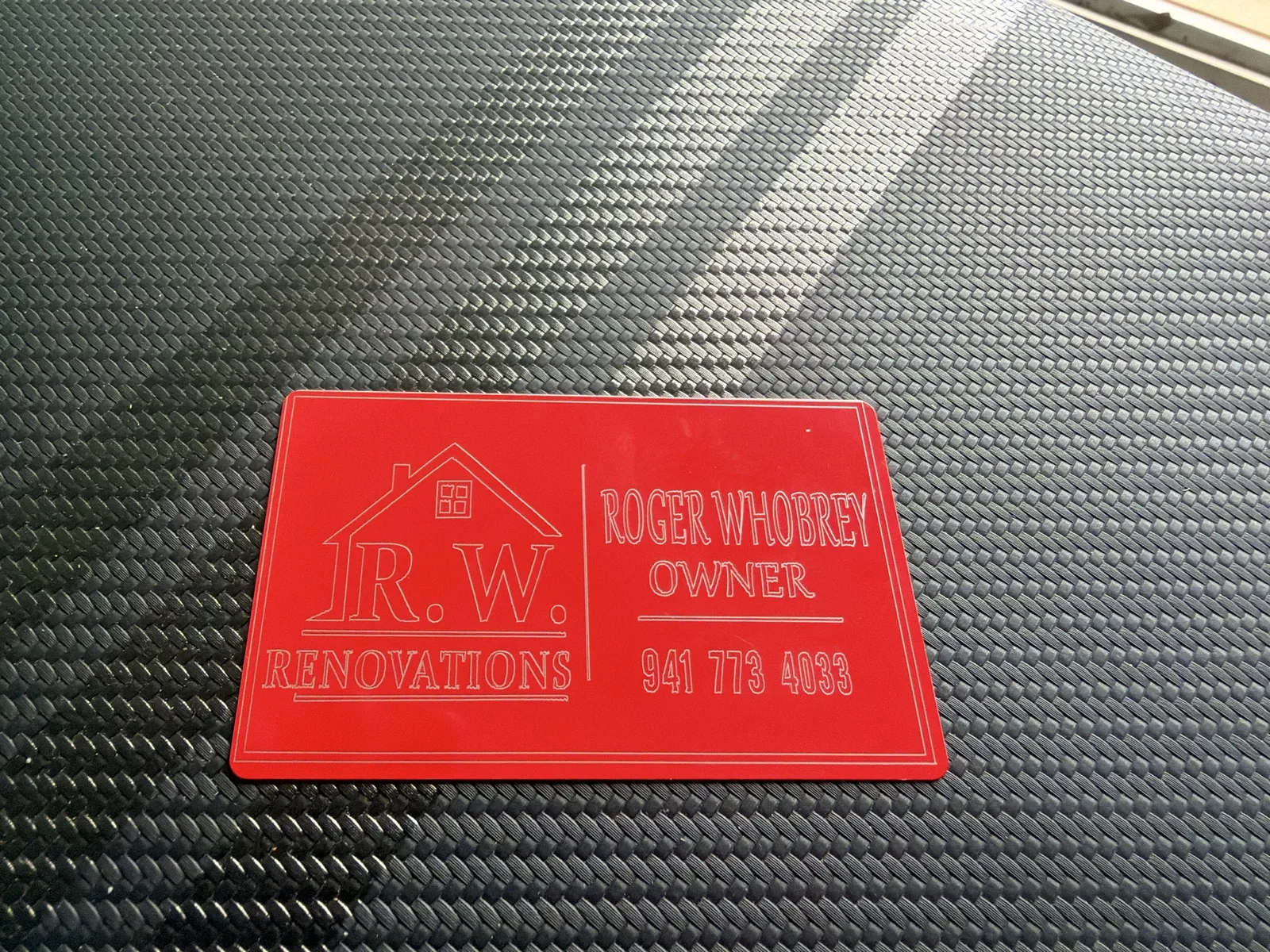 Red engraved metal business card for R.W. Renovations with house icon logo, owner Roger Whobrey